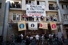 Students protest outside of the SZFE building both on the street and on the building's balcony. 